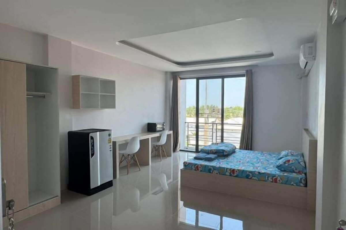 A modern room with a bed, a desk, and a refrigerator.