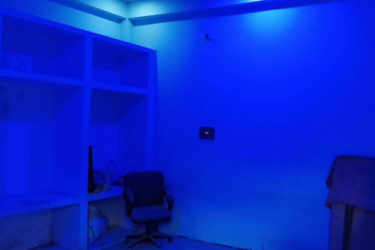 Une pièce à l’ambiance bleutée, avec un bureau et une chaise, ainsi qu’une étagère.