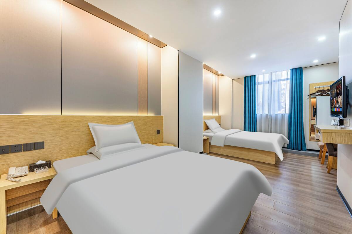 Une chambre d’hôtel avec deux lits, un bureau, une télévision et une armoire.