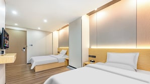 A modern hotel room with two beds, a wooden floor, a flat-screen TV, and a small bedside table. - Guangzhou Kaiyue Hotel Luoxi Subway Station Branch - Free Deliver Service to Canton Fair Complex During Canton Fair Period (Guangzhou)