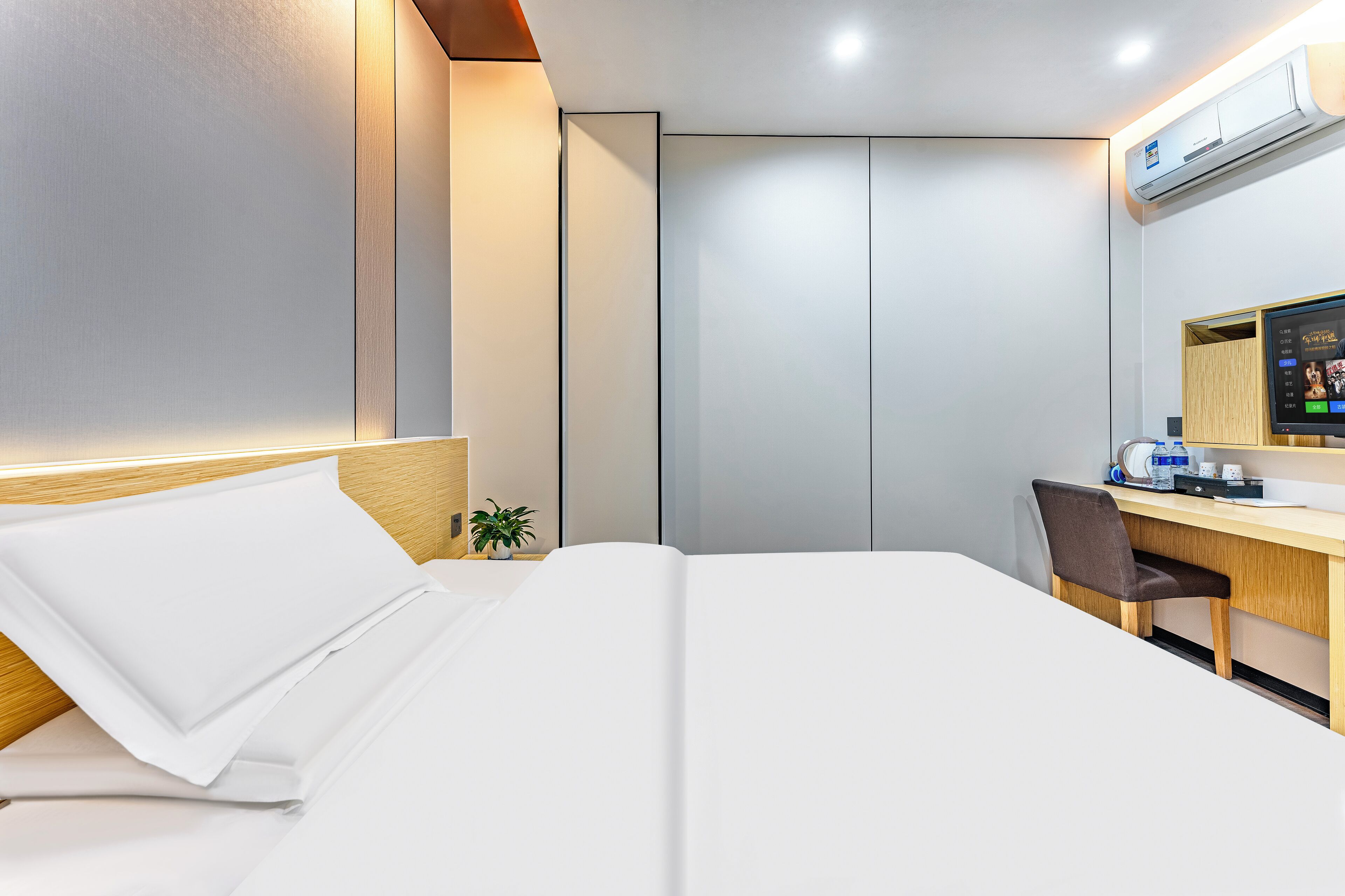 Une chambre d’hôtel équipée d’un lit, d’un bureau, d’une chaise, d’une petite plante et d’un appareil de climatisation.