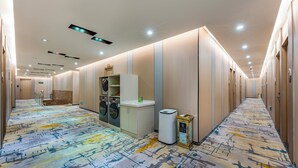 A hotel hallway with a patterned carpet, a laundry area, and a trash bin. - Guangzhou Kaiyue Hotel Luoxi Subway Station Branch - Free Deliver Service to Canton Fair Complex During Canton Fair Period (Guangzhou)