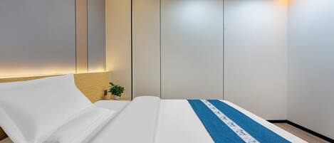 Una habitación de hotel moderna con una cama bien hecha, una pequeña planta en la mesita de noche y un armario empotrado.