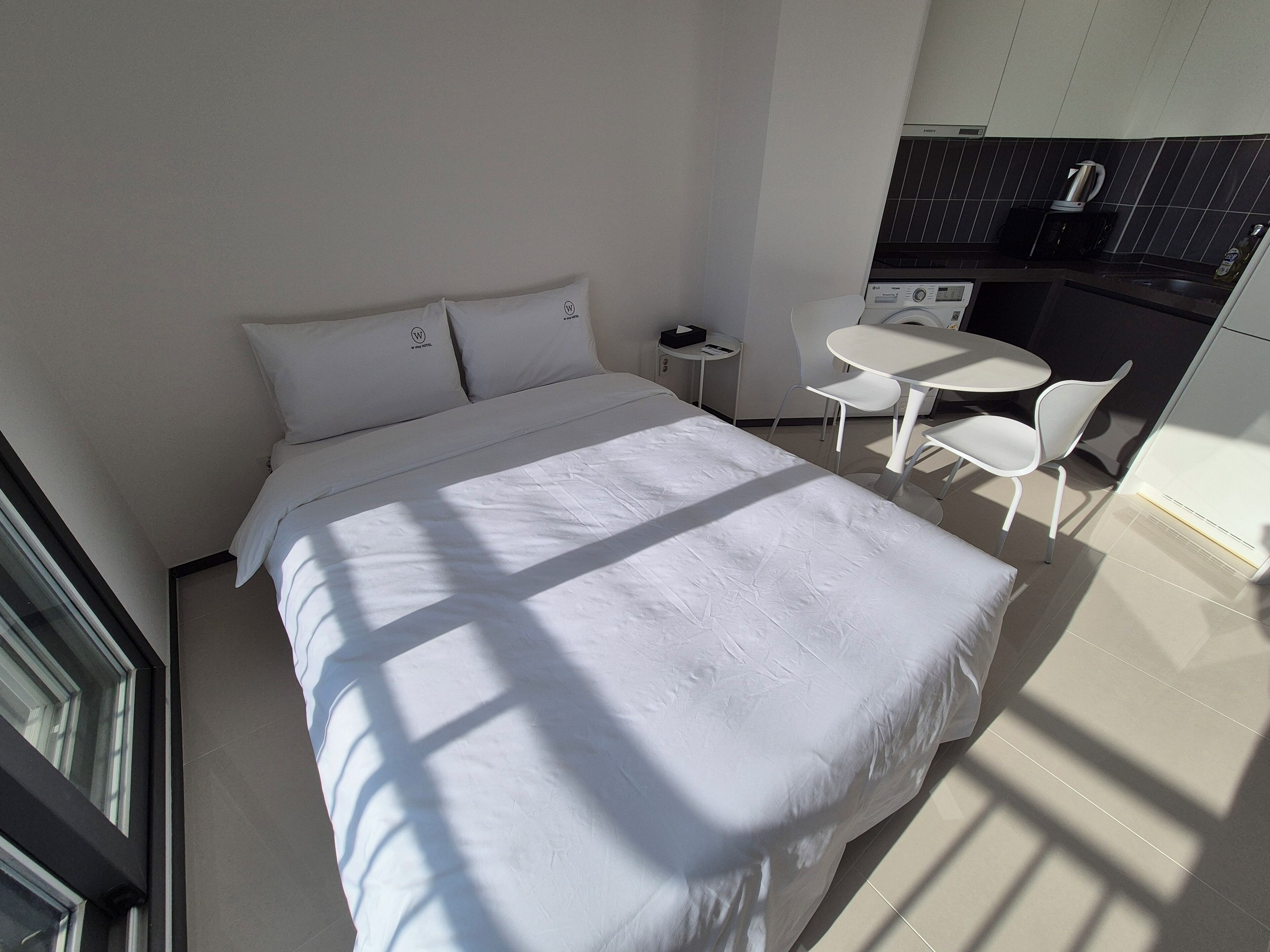 Una habitación de hotel moderna con una cama grande, una pequeña mesa de comedor y una kitchenette.