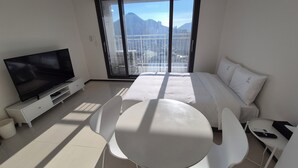 A modern hotel room with a large bed, a TV, a balcony with a city view, and a dining area with chairs and a table. - W Stay Hotel Busan City Hall (Busan)