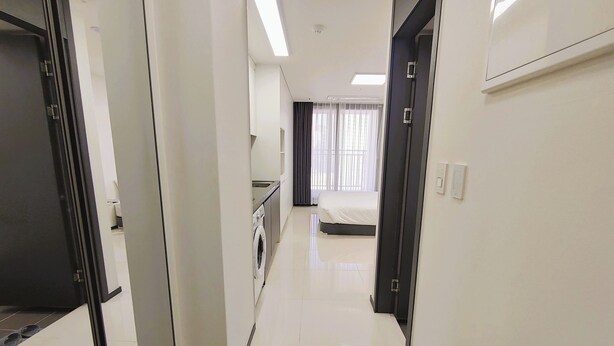 A hotel corridor with a bed, a washing machine, and a bathroom visible in the background. - W Stay Hotel Busan City Hall (Busan)