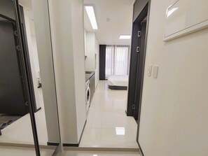 A hotel corridor with a bed, a washing machine, and a bathroom visible in the background. - W Stay Hotel Busan City Hall (Busan)