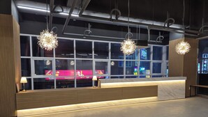 A modern reception desk with a marble countertop, wooden paneling, and pendant lighting. - W Stay Hotel Busan City Hall (Busan)