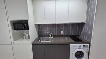 Cocina compacta con microondas, lavabo, hervidor y lavadora.