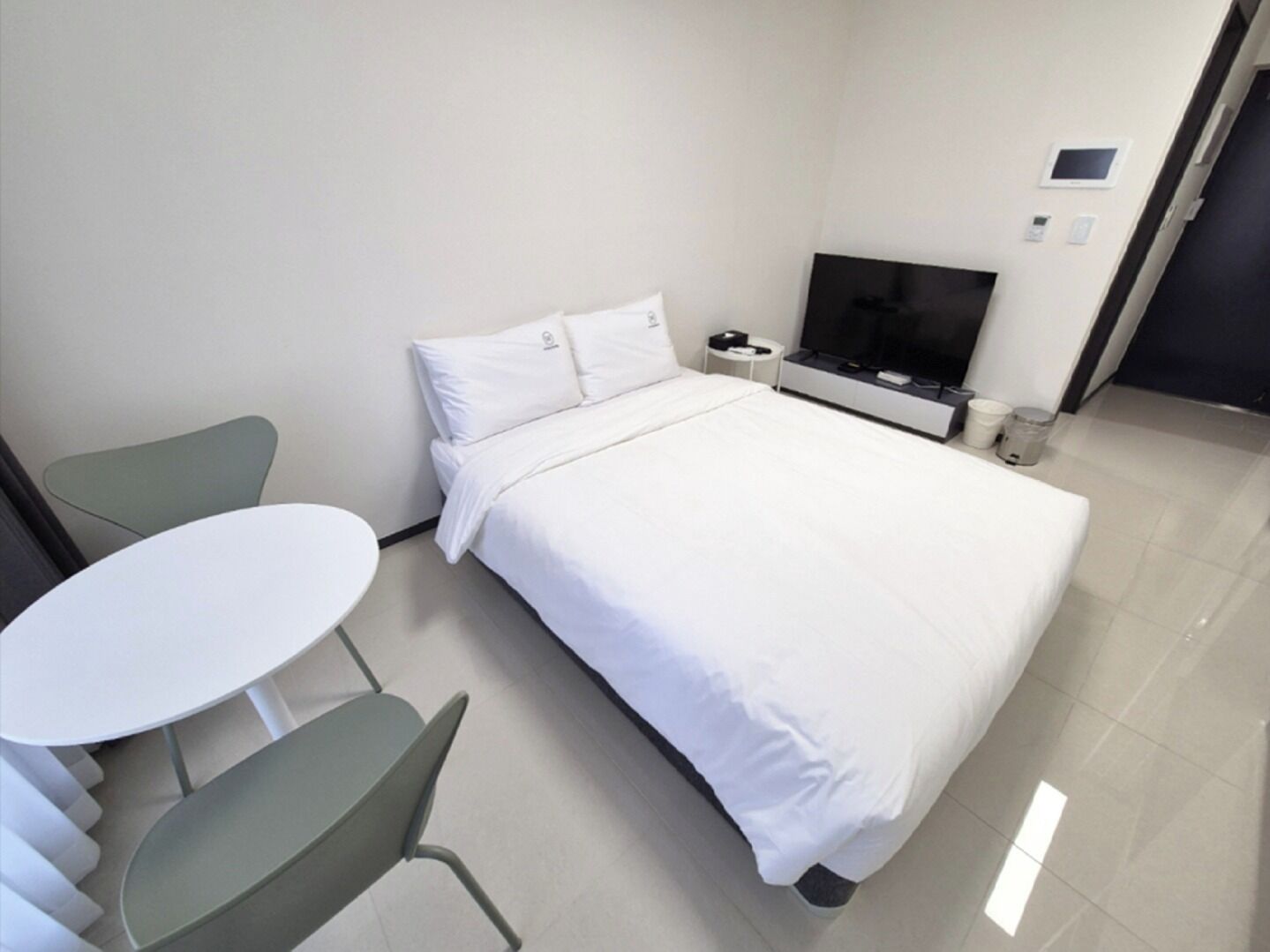 Una habitación de hotel con cama, televisor, una mesita y una silla.