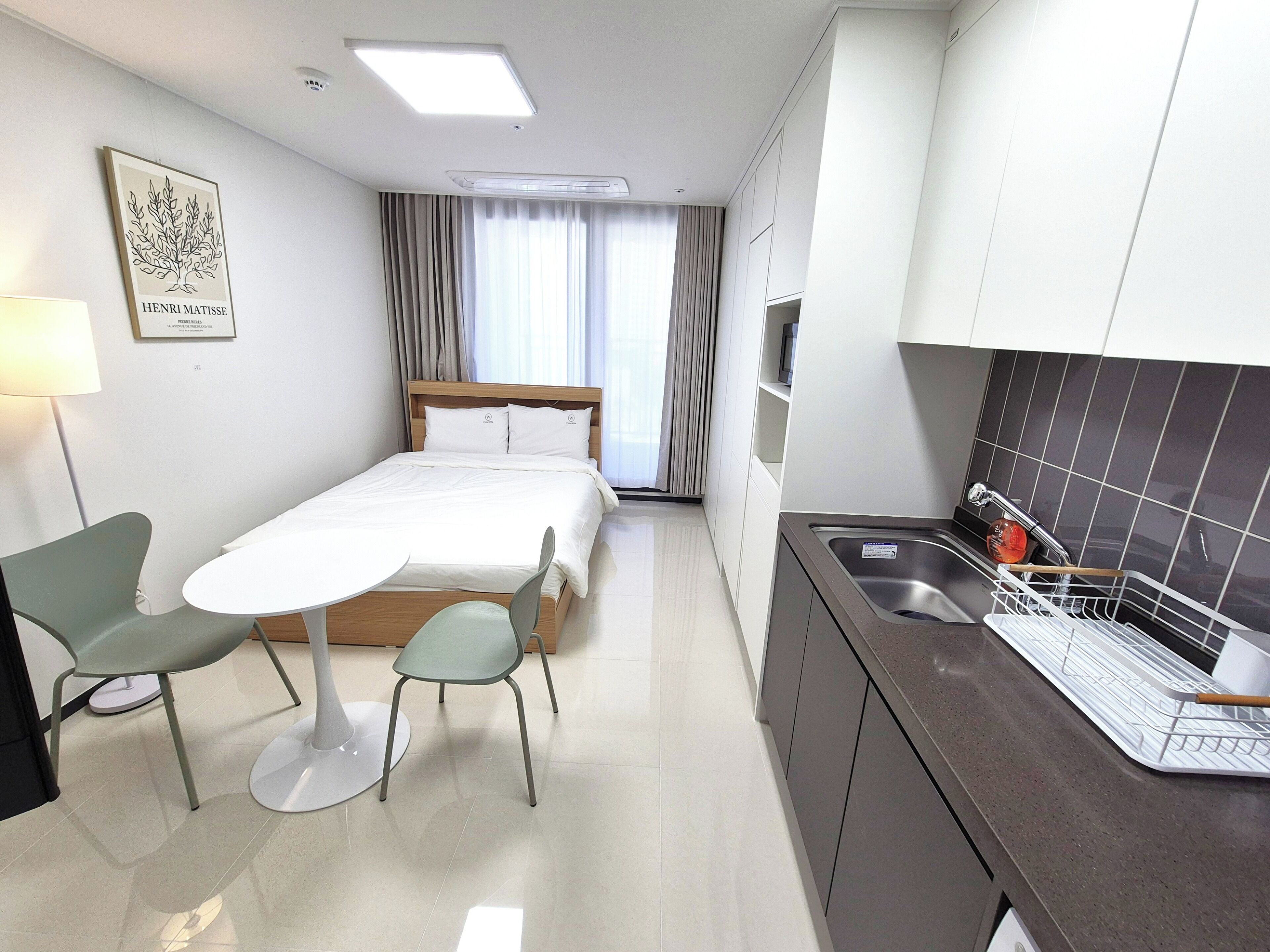 A compact hotel room with a bed, a small dining table, and a kitchenette.