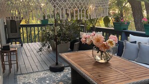Eine Holzterrasse mit Tisch und Stühlen, umgeben von einem gemusterten Teppich.