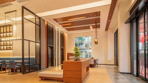 A modern interior with a wooden ceiling, a seating area with a bench and chairs, a wooden sideboard, and a large window providing a view outside.