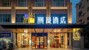 A hotel entrance with illuminated signage, large windows, and a modern facade.