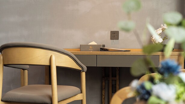 A modern office chair with a wooden frame and grey cushion, positioned in front of a desk with a laptop and a small plant. - Trendy Romantic Hotel Guangzhou Panyu Qiaonan Aoyuan Plaza Branch - Free Deliver Service to Canton Fair Complex During Canton Fair Period (Guangzhou)