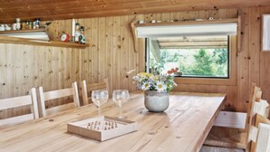 A wooden dining table with chairs, a vase with flowers, and three wine glasses. - "Urban" - 140m from the sea by Interhome (Martofte)