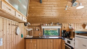 A compact kitchen with wooden paneling, a window, a sink, a stove, and a coffee maker. - "Urban" - 140m from the sea by Interhome (Martofte)