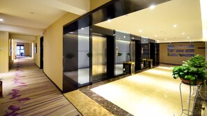 Un hall de hotel con piso de mármol, mostrador de recepción y una planta grande en maceta.