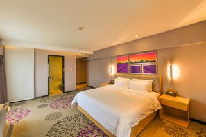 Een hotelkamer met een groot bed, een nachtkastje, een aan de muur bevestigde televisie en een deur naar een badkamer.