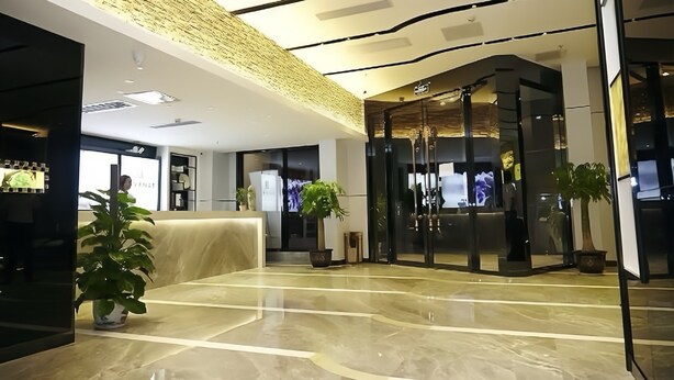 Un vestíbulo moderno con piso de mármol, una recepción y plantas en macetas.