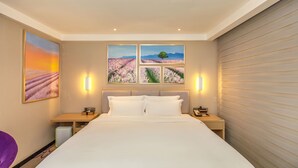 Habitación de hotel con una cama grande, dos mesitas de noche y un televisor montado en la pared.