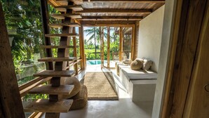Un escalier en bois mène à un espace piscine offrant une vue sur les palmiers.