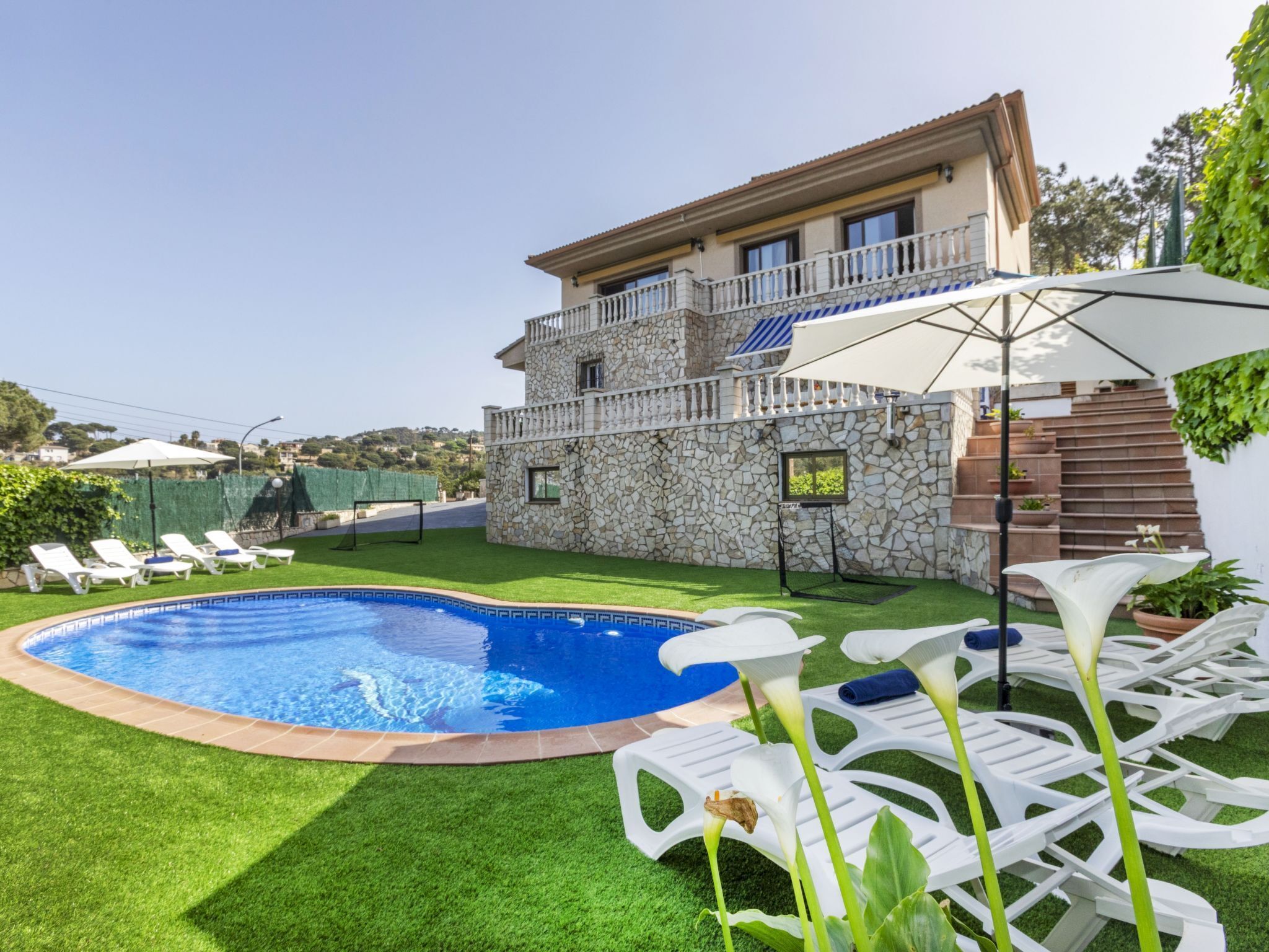 A poolside area with a stone building, a pool, and white lounge chairs.