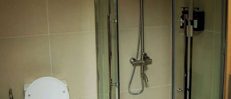 Un baño moderno con ducha de vidrio, inodoro blanco y lavamanos negro.