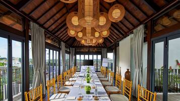 A long dining table with chairs, a large screen, and a view of the city.