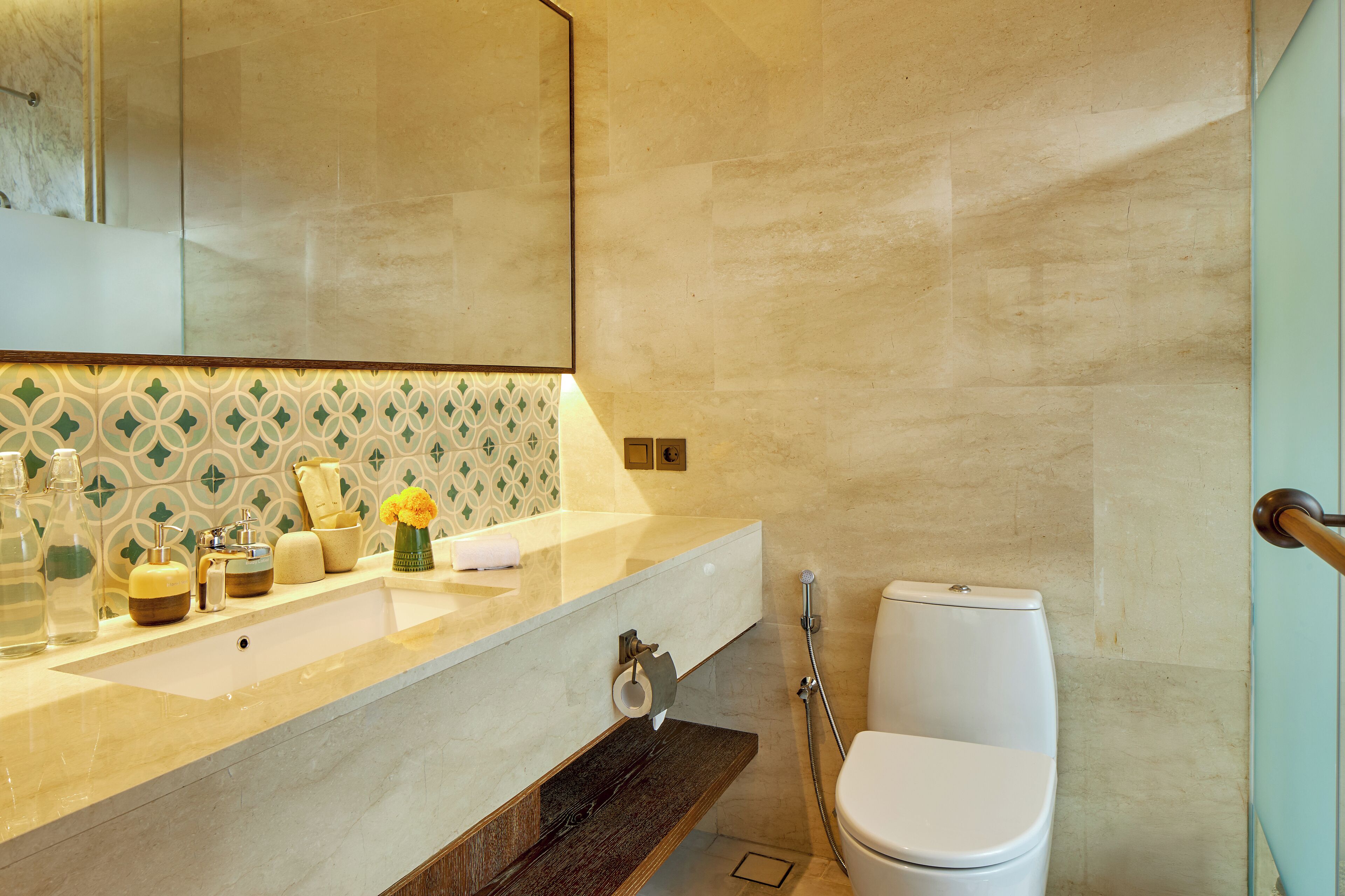 A bathroom with a large mirror, a sink with toiletries, a toilet, and a shower area.