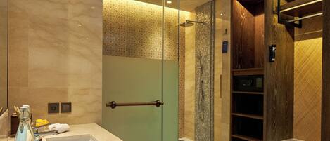 A modern bathroom with a glass shower enclosure, a vanity with a sink, and a built-in storage unit.