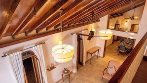 An interior view of a room with exposed wooden beams, a dining area with a table and chairs, and a hanging light fixture. - Rosastays Panjim Goa (Panaji)