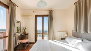A bedroom with a large bed, a desk, a chair, a window with curtains, and a view of the outdoors. - Ilios Kefalonia With 3 Bedrooms and 3 Bathrooms (Kefalonia)