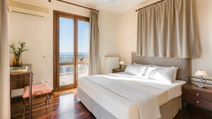 A bedroom with a large bed, a desk, a chair, a nightstand, and a view of the outdoors. - Ilios Kefalonia With 3 Bedrooms and 3 Bathrooms (Kefalonia)