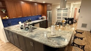 Een moderne keuken met donkere kastjes, een blauwe spatwand en een granieten aanrechtblad.