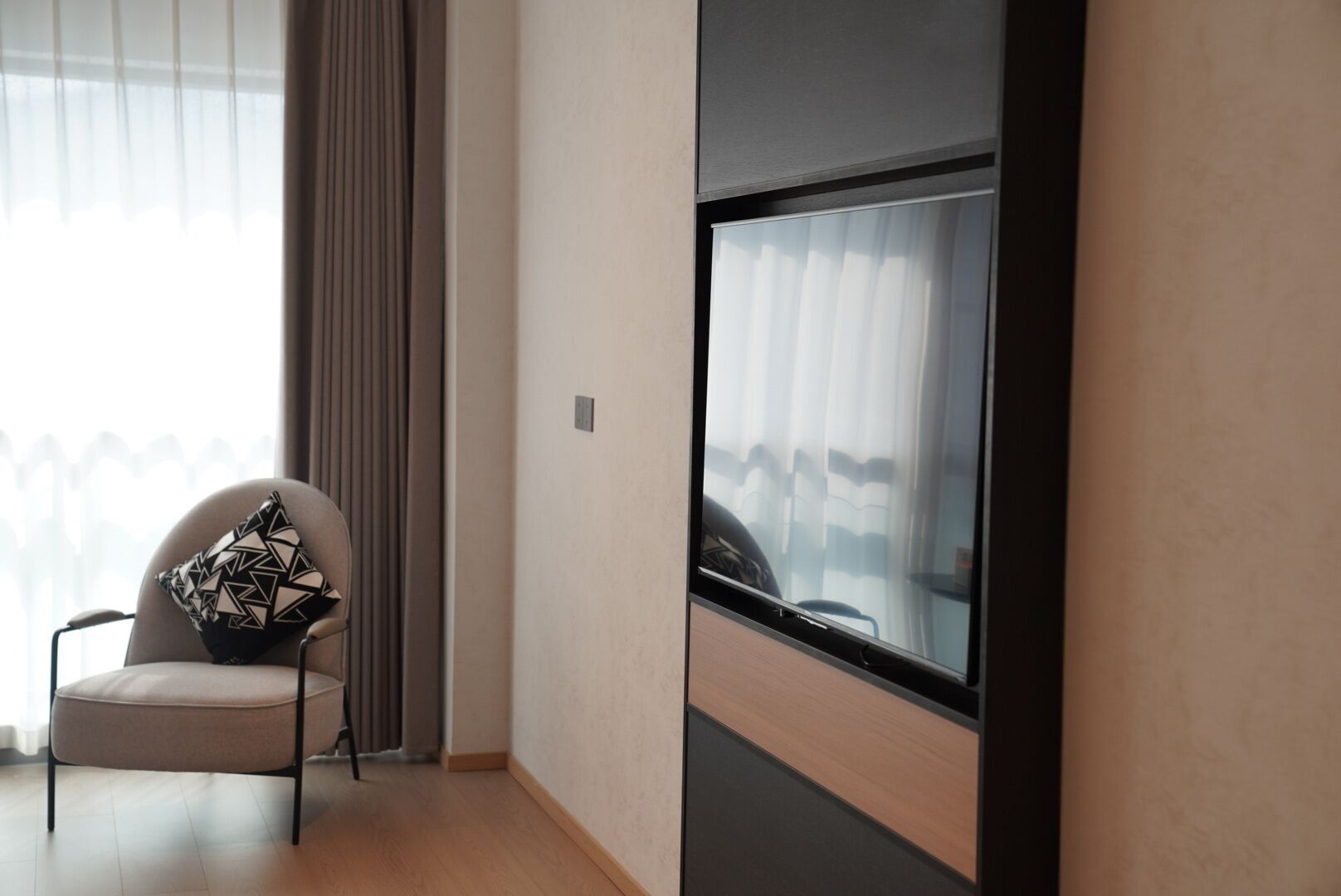 A modern room with a chair, a large window, and a view of the outdoors.