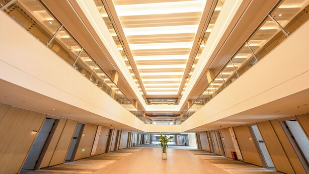 A modern interior with a central walkway, glass railings, and a ceiling with linear lighting fixtures. - LES AIRS (Wenzhou)