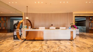 A reception desk with a modern design, a person seated behind it, and a large digital screen displaying an image. - LES AIRS (Wenzhou)