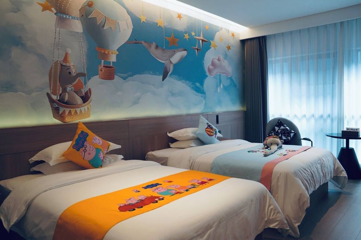 Ein Hotelzimmer mit zwei Betten, einem Wandgemälde und Blick auf die Stadt.