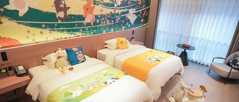 A hotel room with two beds, a mural on the wall, a small table, and a scooter.