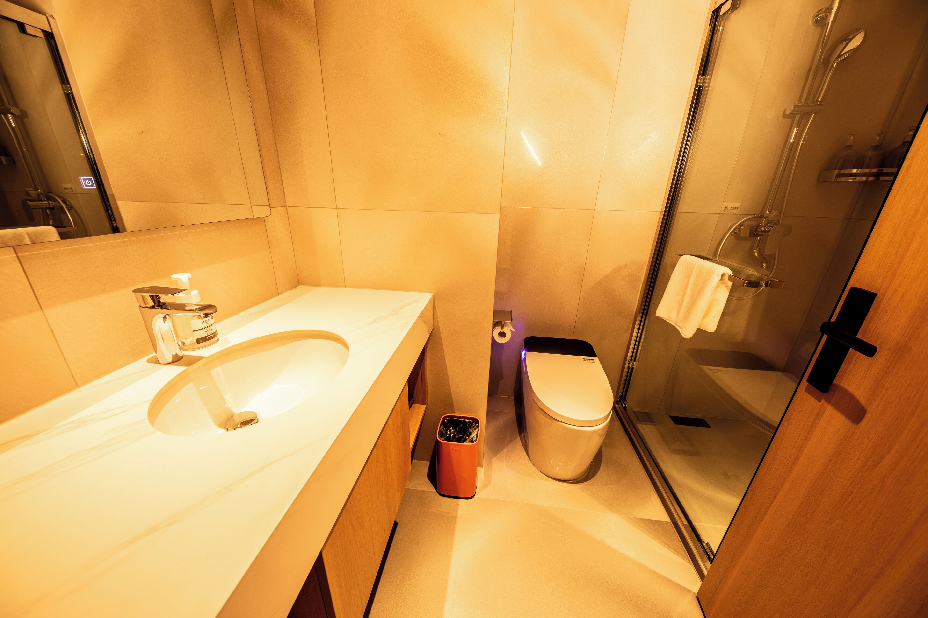 Un baño moderno con lavamanos, inodoro y cabina de ducha con mampara de vidrio.