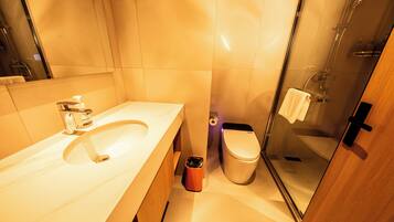 Un baño moderno con lavamanos, inodoro y cabina de ducha con mampara de vidrio.