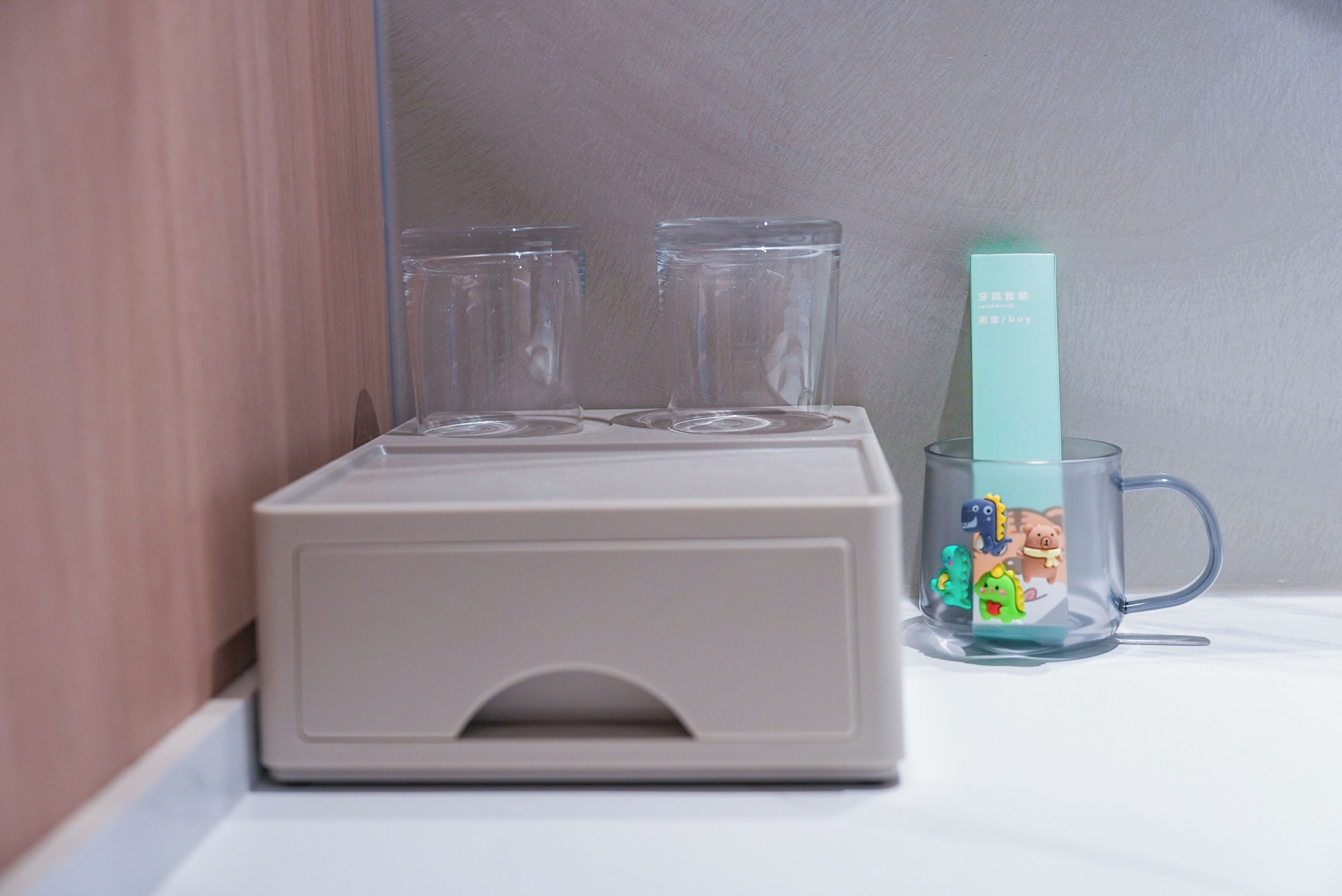 A kitchen area with a white countertop, a coffee maker, and two clear glasses.