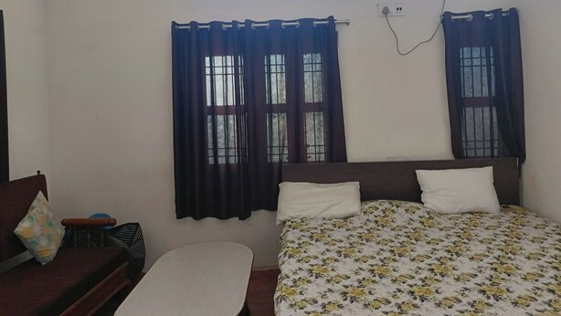 A room with a bed, a small table, and a window with curtains.
