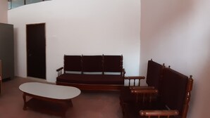 A small, compact room with a bed, a sofa, a small table, and a chair.