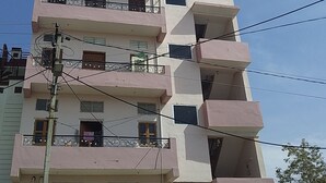 A multi-story residential building with balconies, air conditioning units, and visible power lines.