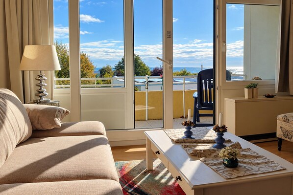 A living room with a sofa, a coffee table, and a view through a sliding glass door to the outside.