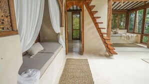A room with a wooden staircase, a bed with a canopy, and a view of the outdoors.