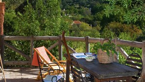 Une terrasse en bois avec une table et des chaises, un panier en osier et un livre.