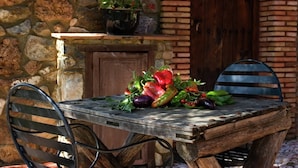 A rustic outdoor table with a variety of vegetables, set against a stone wall and wooden door. - El Búho, Cottage in Alájar (Alájar)